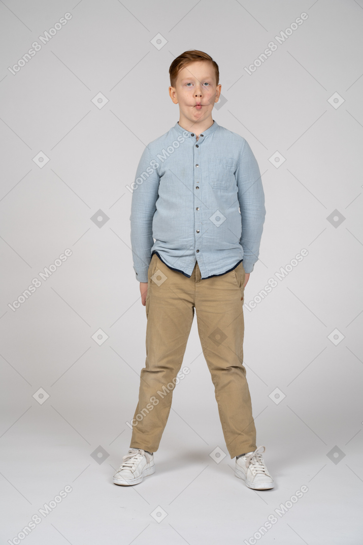 Front view of a boy in casual clothes making faces and looking at camera