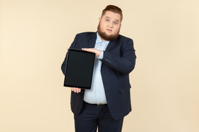 Jovem homem com excesso de peso, segurando o tablet digital verticalmente