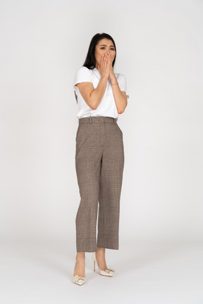 Front view of a scared young lady in breeches and t-shirt touching her mouth
