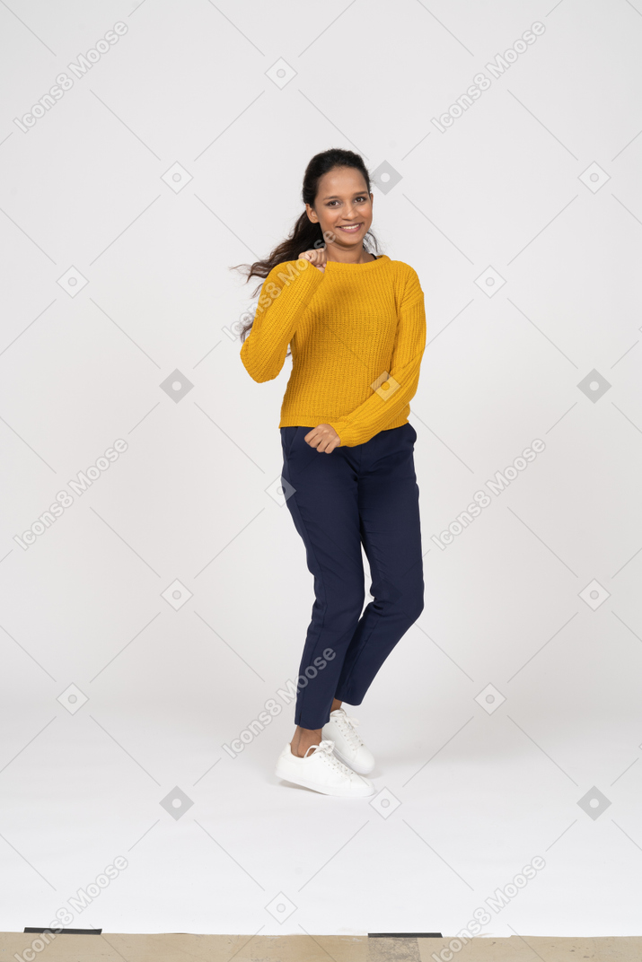 Front view of a happy girl in casual clothes running