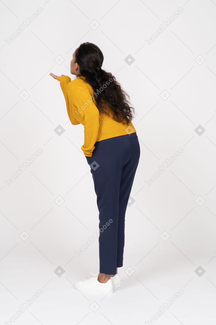 Side view of a girl in casual clothes blowing a kiss