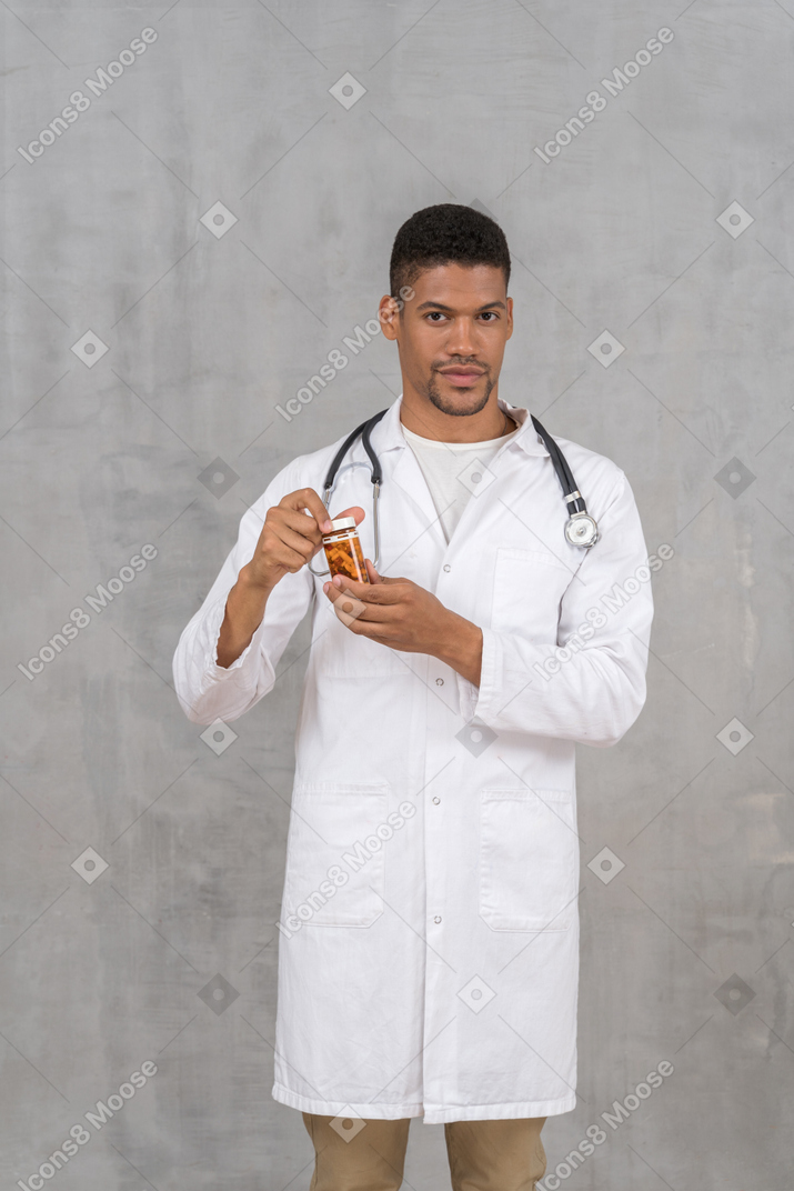 Medico maschio che tiene una bottiglia di pillole