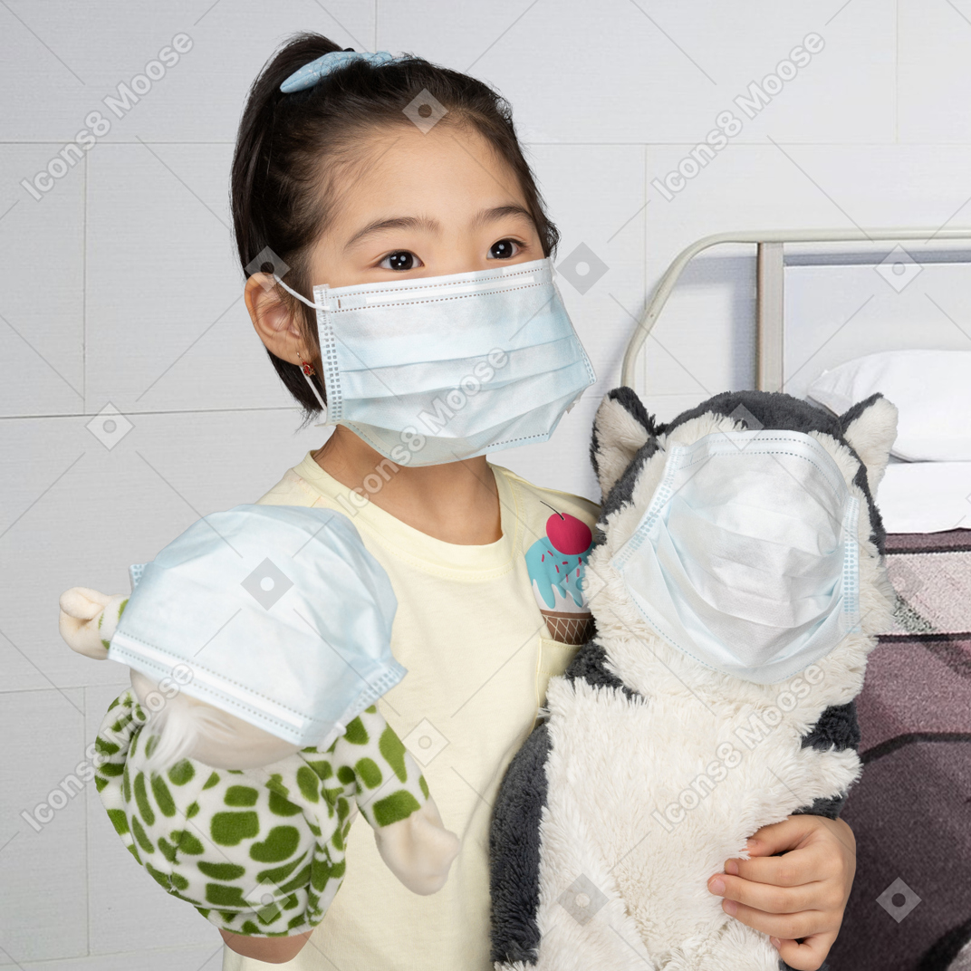 A little girl in face mask holding toys in face masks