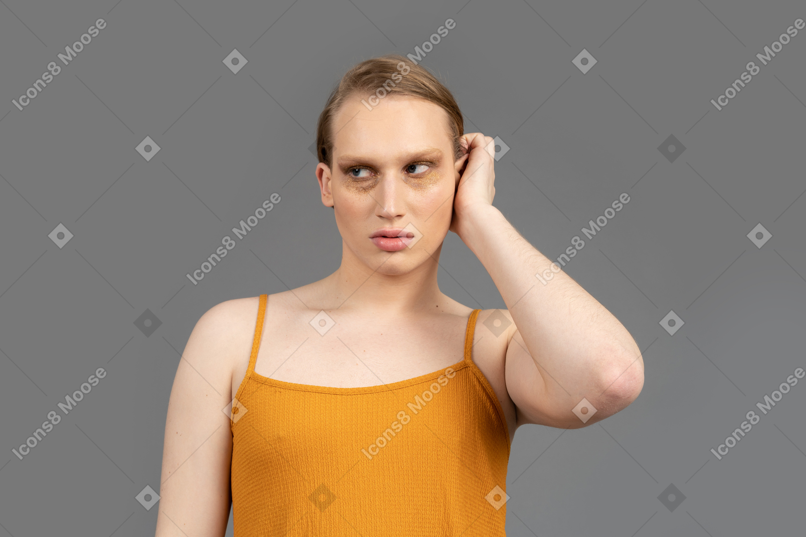 Close-up of a young non-binary person touching side of their head