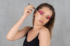 Portrait of a young woman putting eyeshadow on