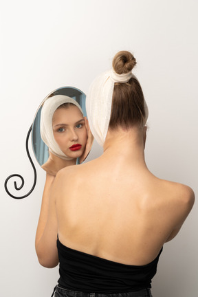 Young woman with head bandage looking in the mirror