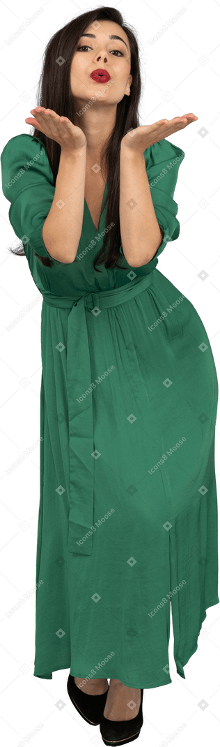 Vista frontal de uma jovem de vestido verde enviando um beijo no ar