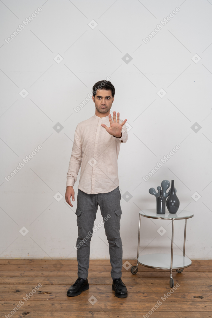 Front view of a man in casual clothes showing stop gesture