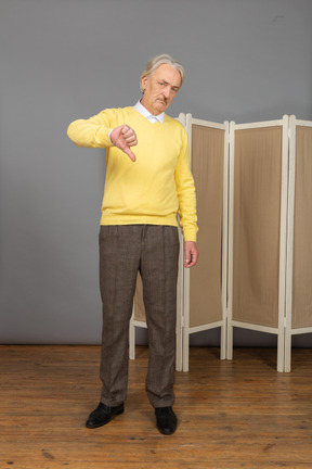 Vista frontal de um homem idoso aborrecido colocando o polegar para baixo