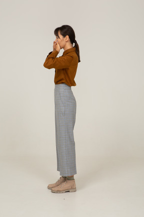 Side view of a young asian female in breeches and blouse touching her face