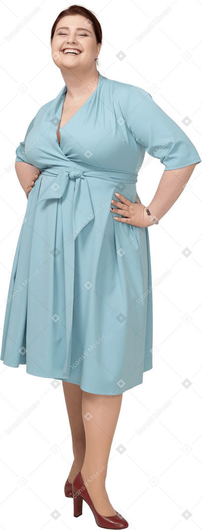 腰に手を置いて立っている青いドレスの幸せな女性の正面図