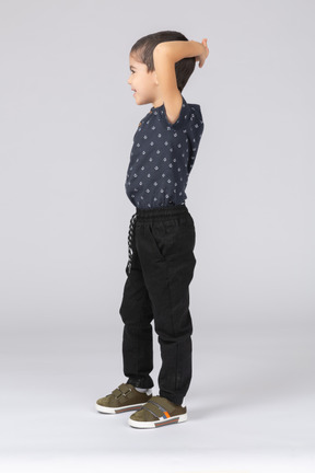 Vue latérale d'un garçon mignon posant avec les mains derrière la tête