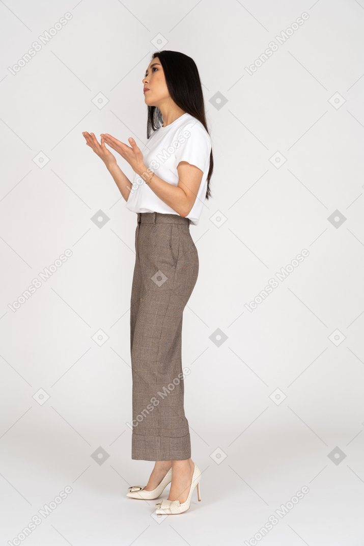 Three-quarter view of a gesticulating young lady in breeches and t-shirt explaining something