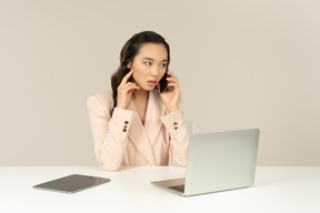 Funcionário de escritório feminino asiático olhando incomodado com telefonema