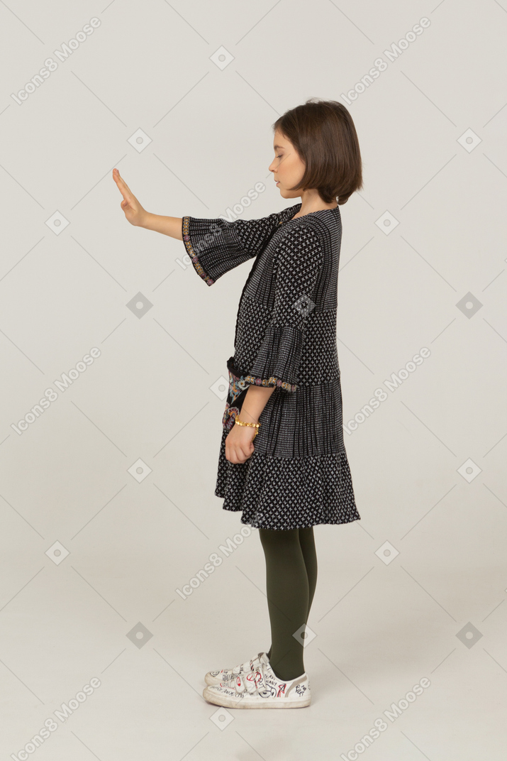 Vista lateral de una niña en vestido extendiendo su mano