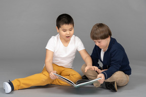Two little friends sharing one colorful book