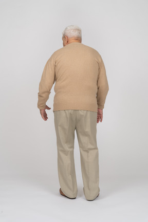 Rear view of an old man in casual clothes walking