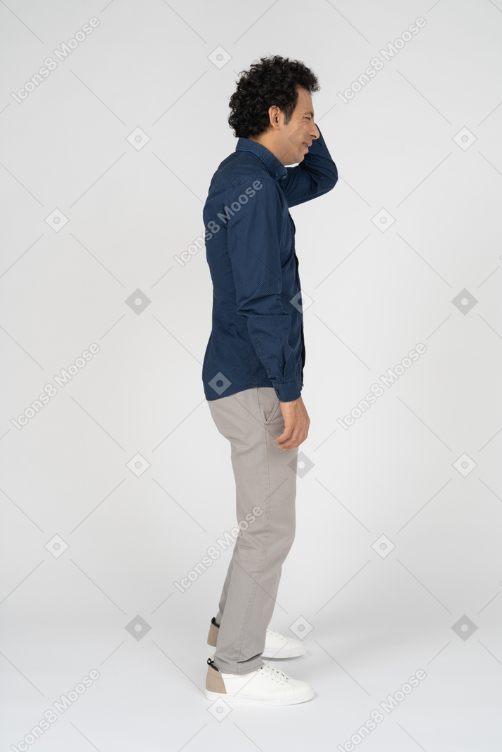 Vista lateral de um homem com roupas casuais coçando a cabeça