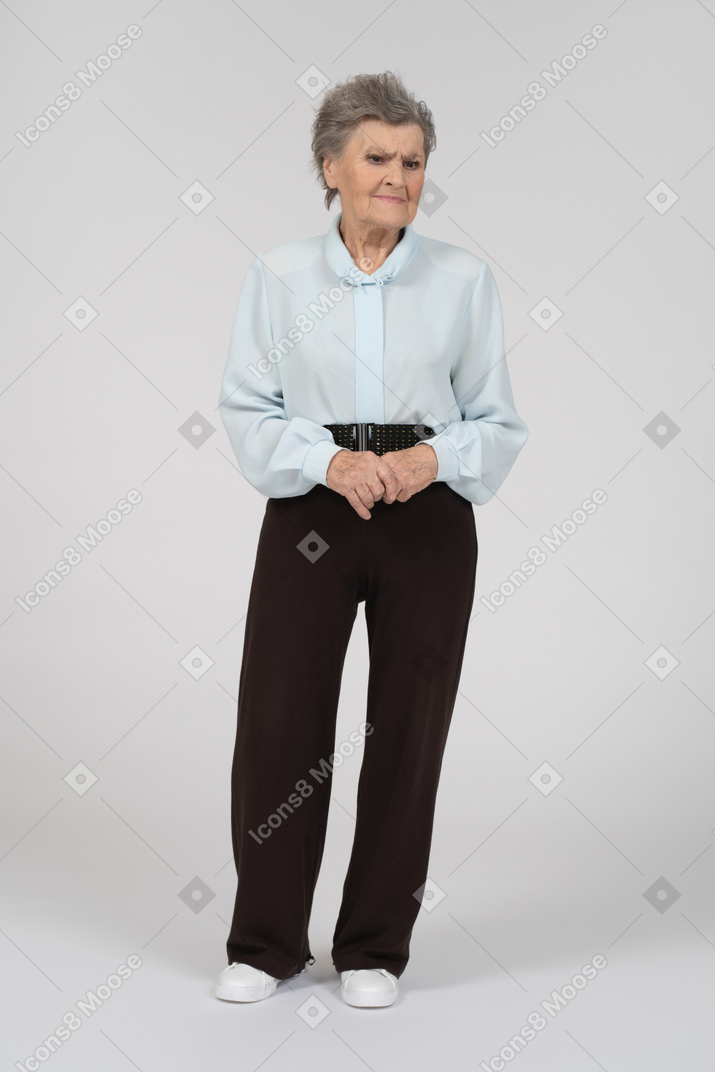 Vista frontal de una anciana que parece triste con las manos entrelazadas