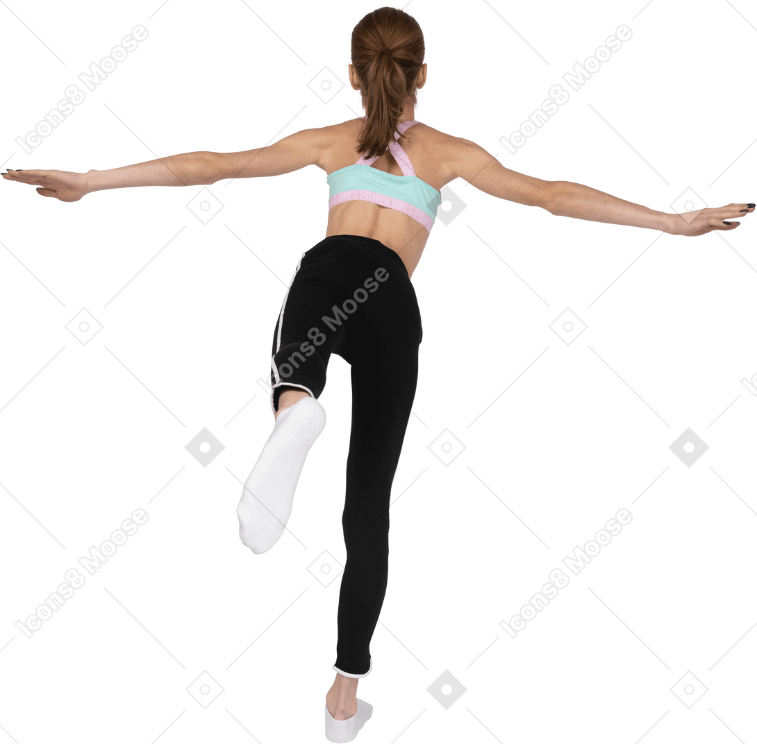 Vista traseira de uma adolescente em roupas esportivas se equilibrando sobre a perna