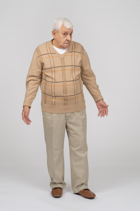 Vista frontale di un vecchio confuso in abiti casual in piedi con le braccia tese