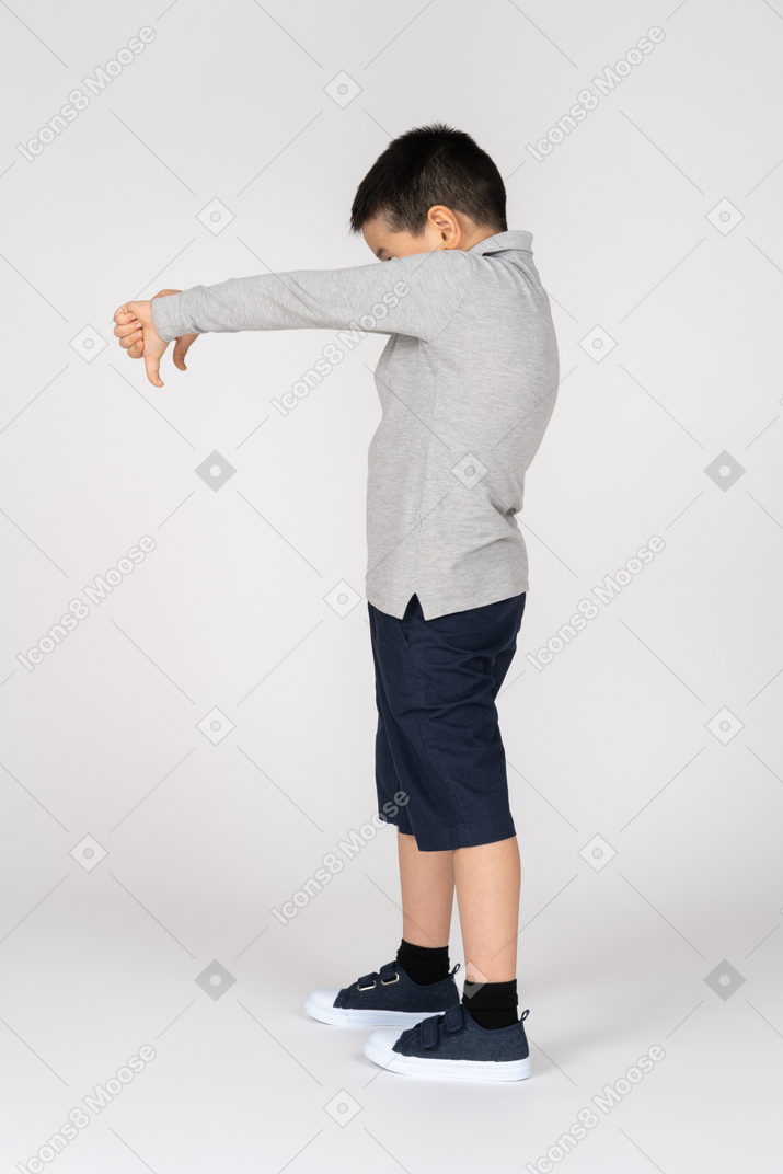 Мальчик стоит и показывает палец вниз