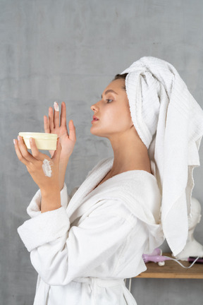 Side view of a woman in bathrobe applying hand cream