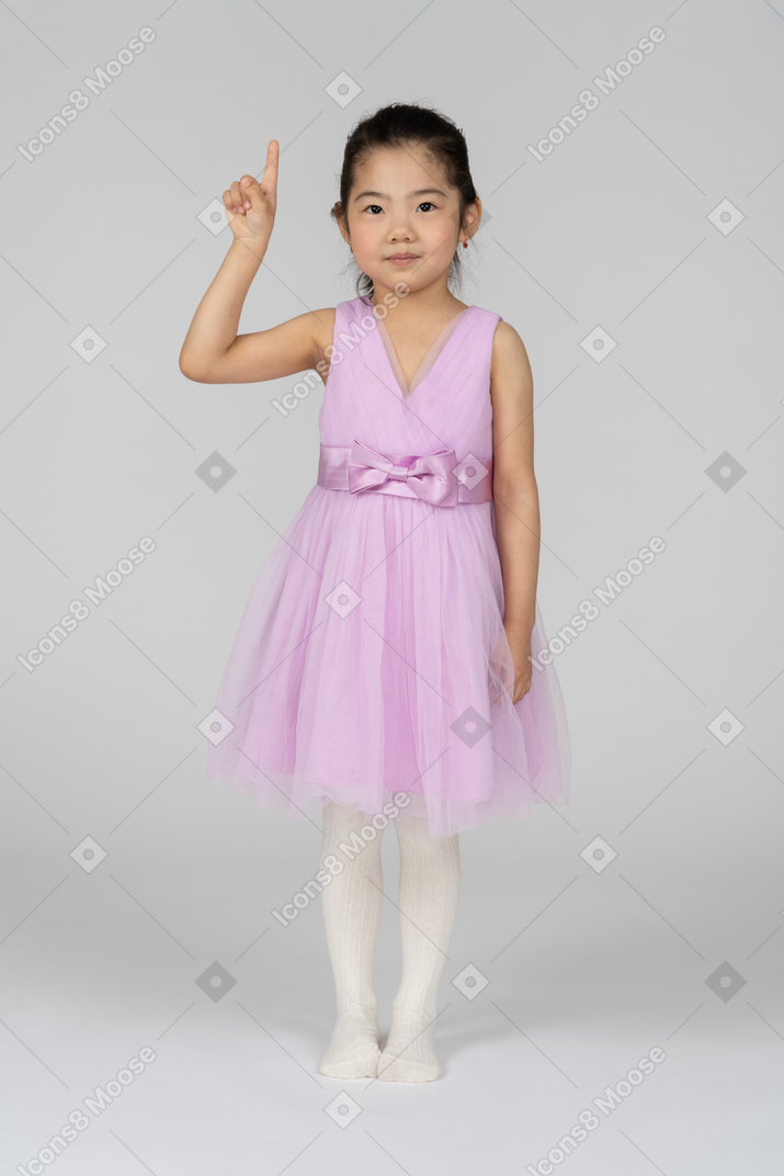Portrait en pied d'une jolie petite fille pointant vers le haut