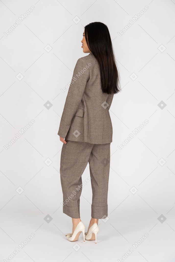Three-quarter back view of a pouting young lady in brown business suit