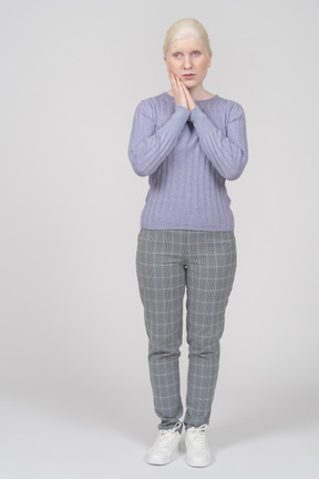 Young woman standing with hands under cheek