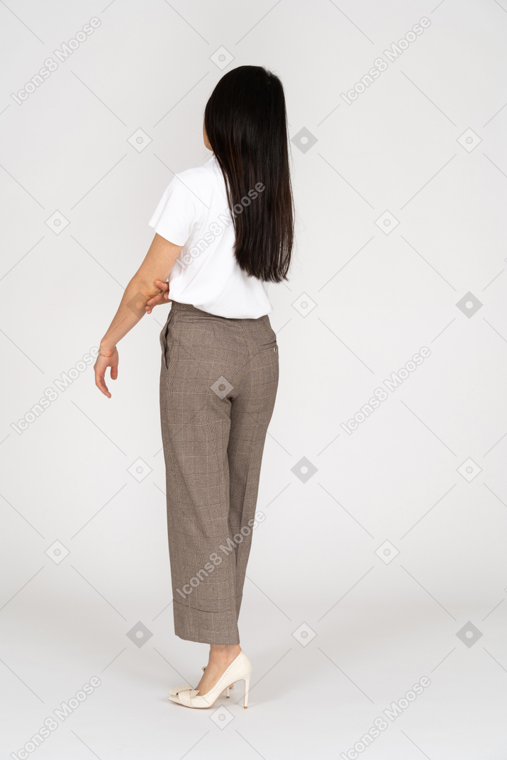 Three-quarter back view of a displeased grimacing young lady in breeches and t-shirt
