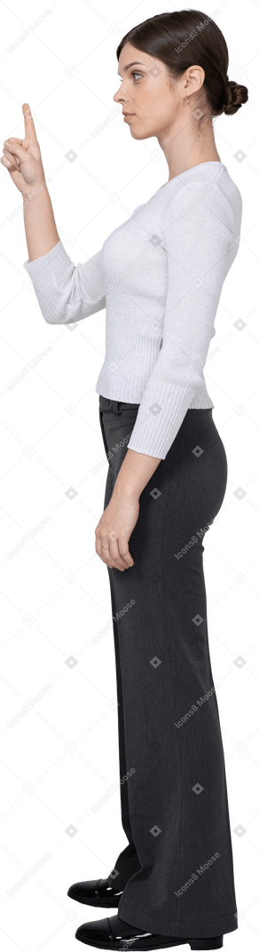 Side view of a young woman in office clothing raising finger