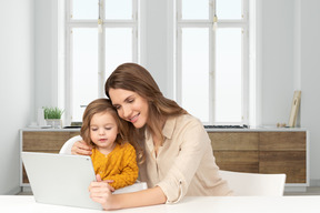 A woman and a child are looking at a laptop