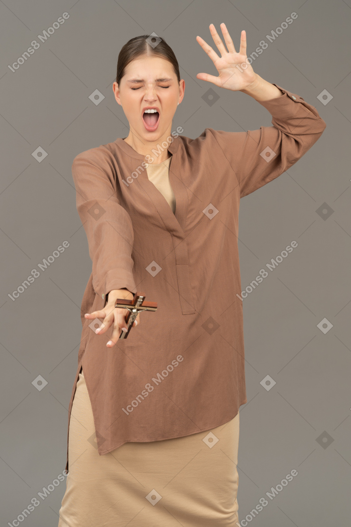 Young christian woman screaming and throwing a cross