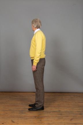 一位老人在黄色套衫转头，看着别处的侧视图