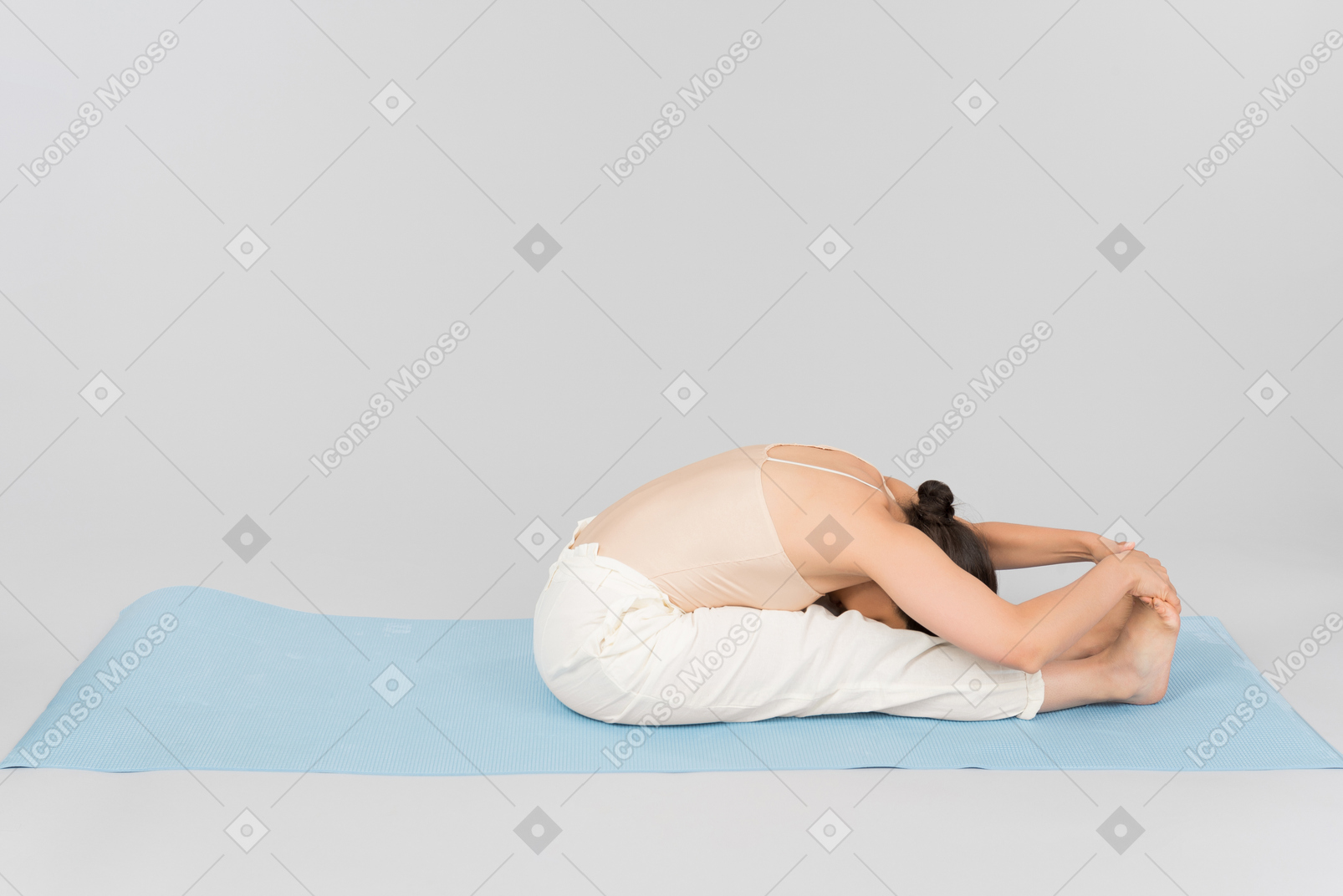 年轻的印度女人坐在瑜伽垫上折叠