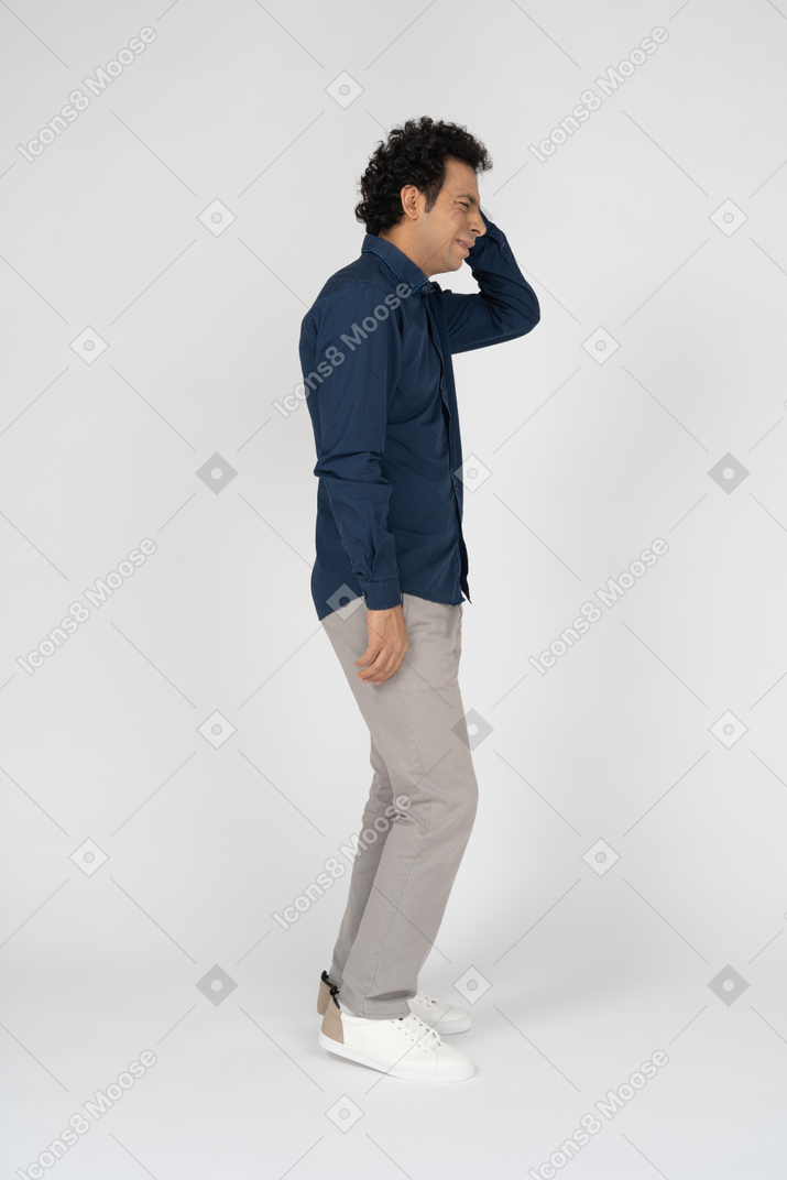 Side view of a man in casual clothes scratching head