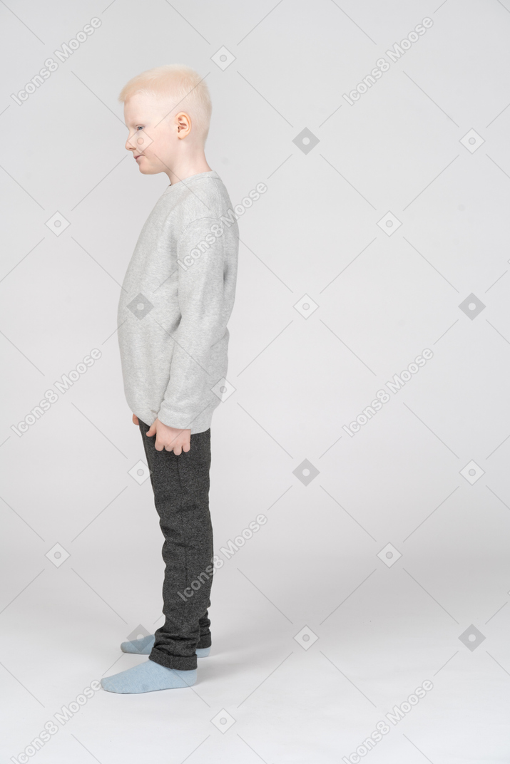 Vista laterale di un ragazzino in abiti casual che osserva da parte