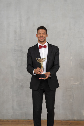 Hombre feliz con traje posando con un premio