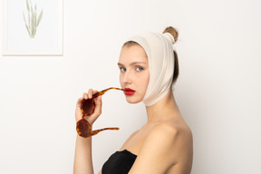 Вид сбоку женщины с повязкой на голове, держащей солнцезащитные очки