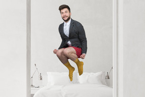 A man in a suit jumping on a bed