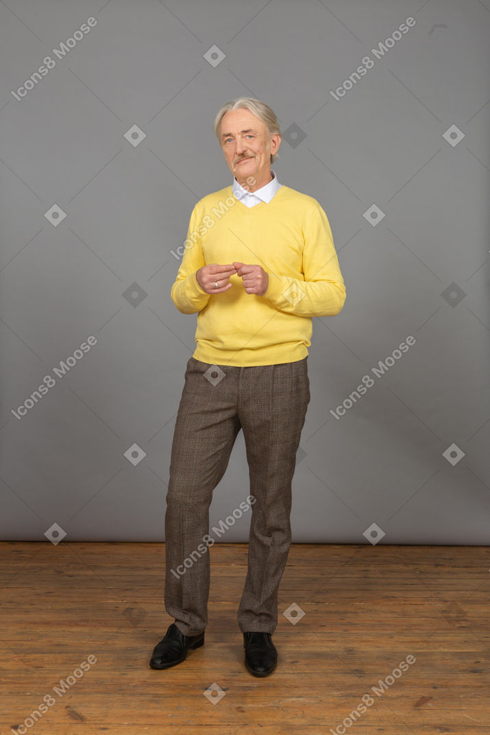 Front view an old smiling man wearing yellow pullover and putting hands together and looking at camera