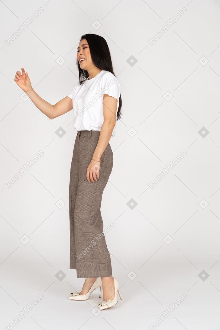 四分之一的观点，在一个年轻的女人，穿着马裤和白色的t恤，显示出某种东西的大小