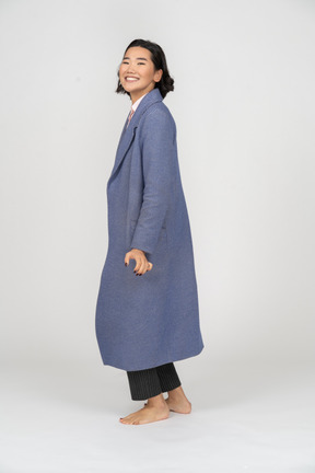 Vista lateral de una mujer sonriente con abrigo