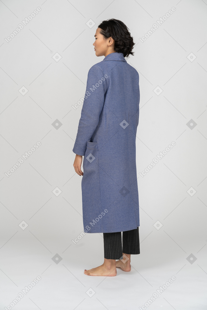 Вид сзади на женщину в пальто, стоящую с руками по бокам