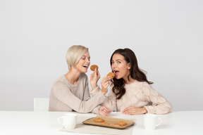 Giovani donne che si nutrono a vicenda con i biscotti