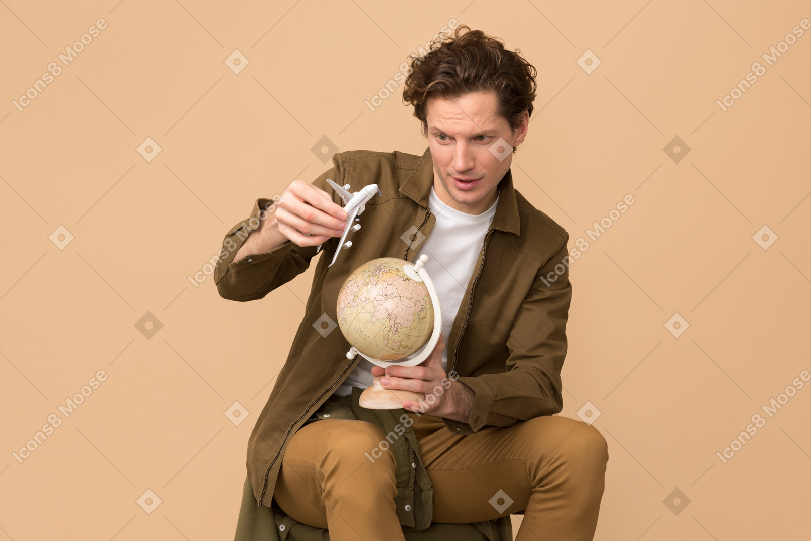 Handsome young traveller holding airplane model over the globe