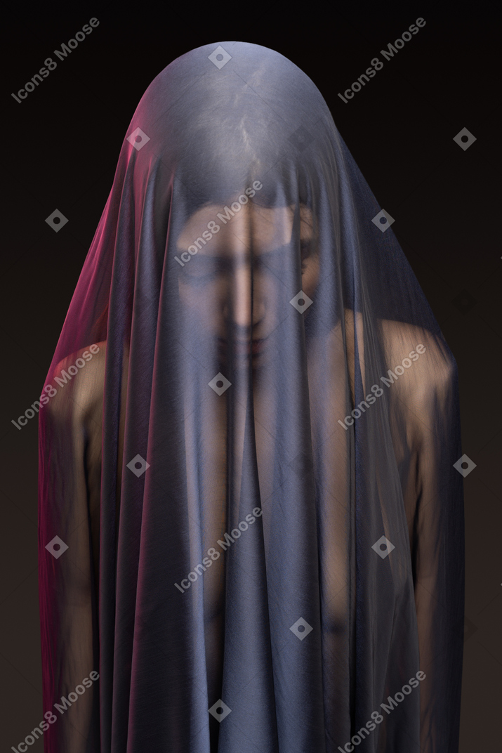 Sensual naked young woman in dark veil looking down