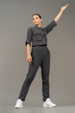 Front view of a young woman in a jumpsuit outstretching her arm