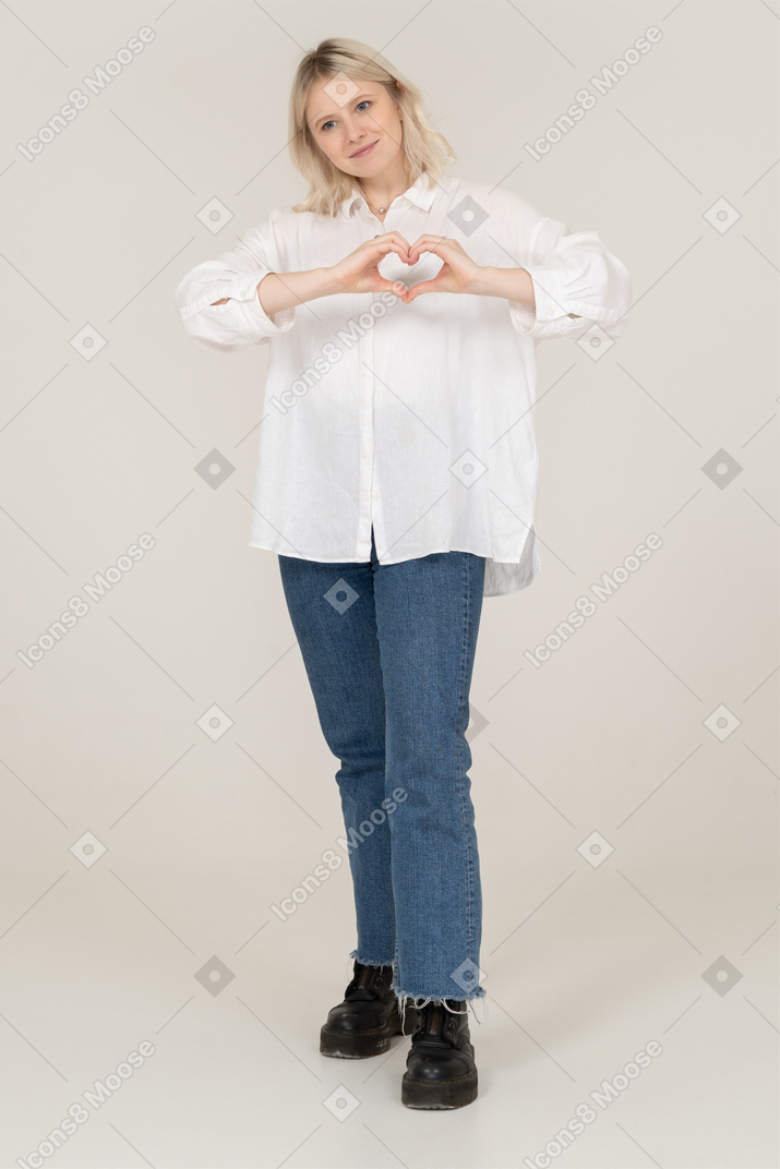 一位金发碧眼的女性，穿着休闲服显示一个心形手势，放在一边看的前视图